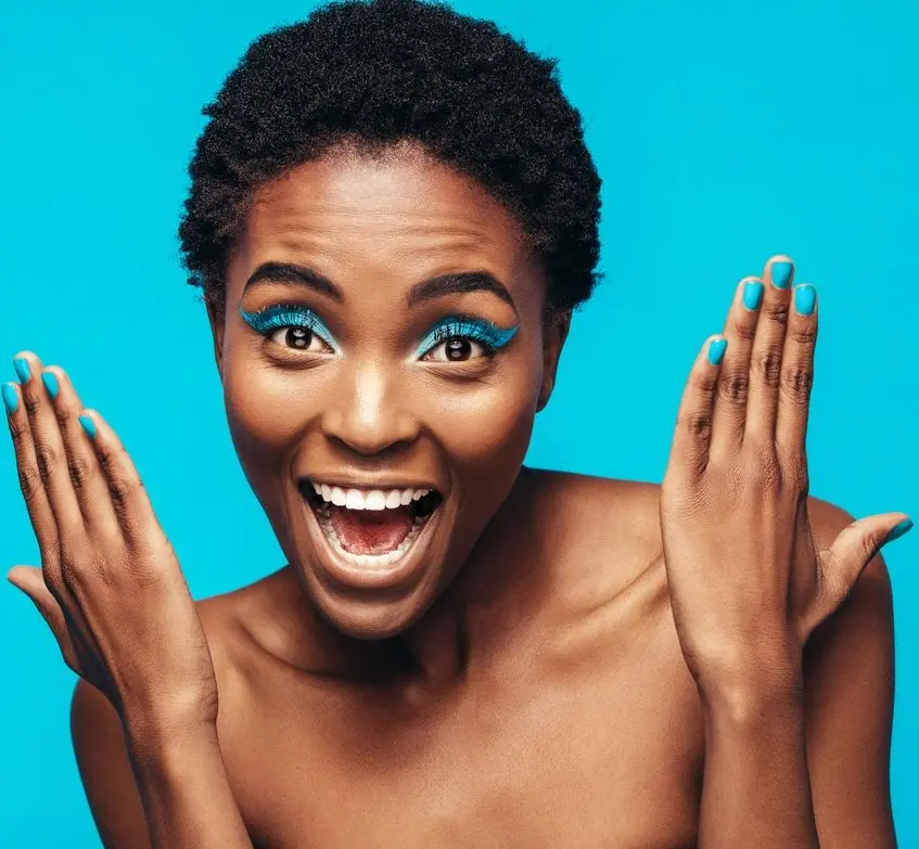 A woman with blue eyes and hands up.